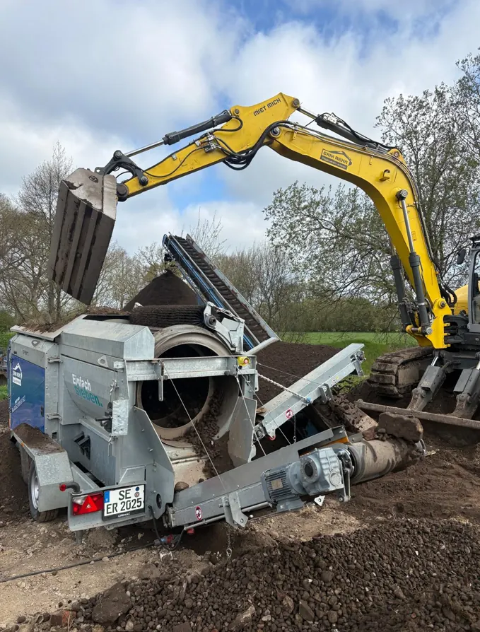 Radmobile Siebtrommel im Einsatz, beschickt von einem Bagger aus dem Mietpark